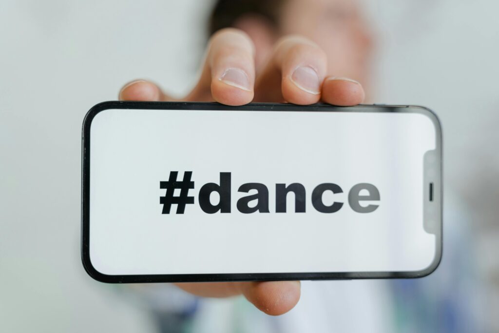 Close-up of a phone screen displaying the #dance hashtag, held by an adult.